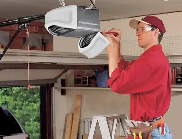 A worker is installing a Chamberlain garage door opener in a garage with tools around.