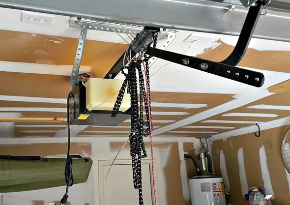 Garage door opener installed on the ceiling with tracks and cables in a home garage.