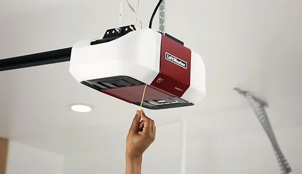 Worker adjusting a garage door opener during installation in a modern garage.