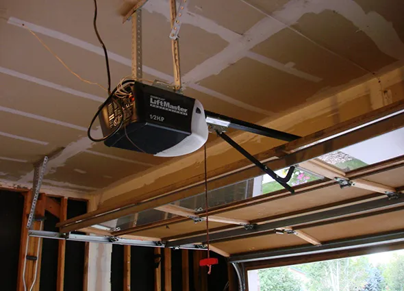 Garage door opener installed on the ceiling with tracks and cables in a garage.