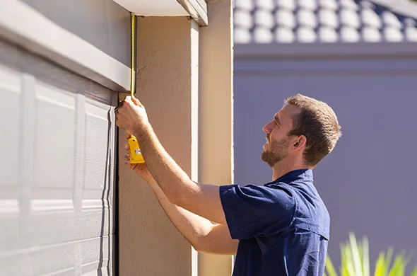 Worker measuring a garage door frame for installing a garage door opener.